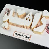 Cake in the shape of Name Letter Cartoon Character With Flowers In Small Size For 5-6 Persons