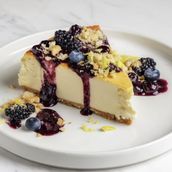 Blueberry Cheesecake Topped With Lemon Wedges And Crumbled Digestives